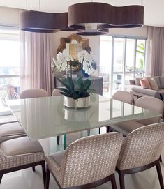 a dining room table with chairs and a vase filled with flowers on top of it