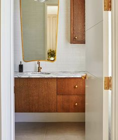 a bathroom with a sink, mirror and wooden cabinets