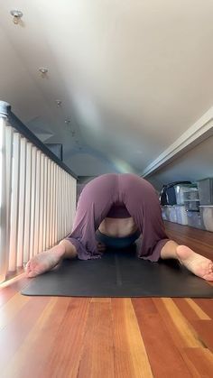 a person is doing yoga on a mat in the middle of a room with wooden floors