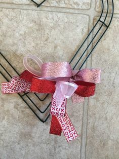 a red and pink ribbon tied to a metal rack with scissors on the top of it