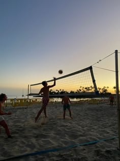 people playing volleyball on the beach at sunset