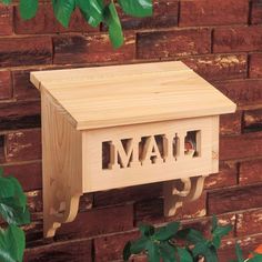 a wooden mailbox with the word mail on it in front of a brick wall