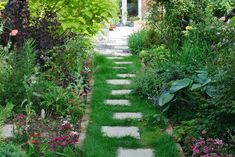 a garden with stepping stones in the grass and flowers on the ground next to it