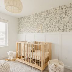 a baby's crib in the corner of a room with floral wallpaper