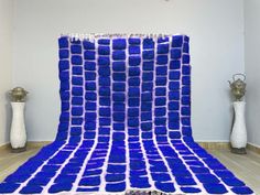 a blue and white blanket sitting on top of a wooden floor next to two vases