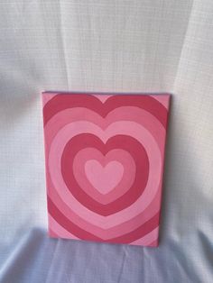 a pink and red heart shaped painting on a white sheet with blue fabric behind it