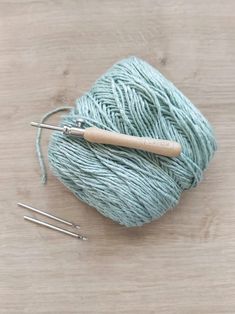 a ball of yarn and knitting needles on a wooden surface