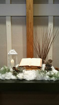 an open book sitting on top of a table next to a candle and some branches