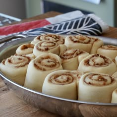 a pan filled with cinnamon rolls on top of a wooden table