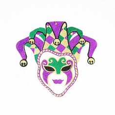 a purple and green mardi gras mask with bells on it's head