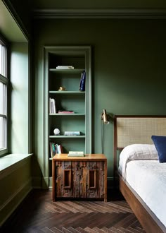 a bed sitting next to a book shelf in a bedroom on top of a hard wood floor