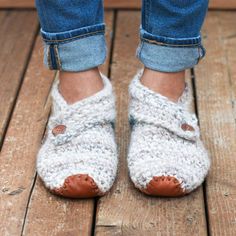 a close up of a person's feet wearing crocheted slippers and jeans