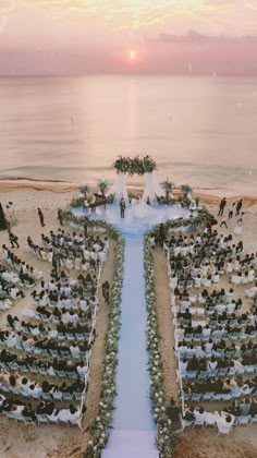 an aerial view of a wedding ceremony on the beach in front of the ocean at sunset