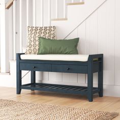 a wooden bench sitting under a stair case next to a green pillow on top of it