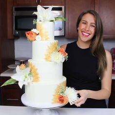 a woman standing in front of a cake with flowers on it