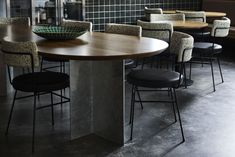 a table with chairs and a bowl on it in a room that has black tile walls