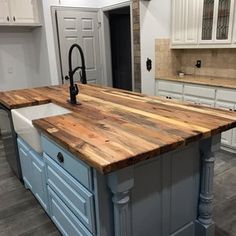 a kitchen island made out of wooden planks in the middle of a room with white cabinets