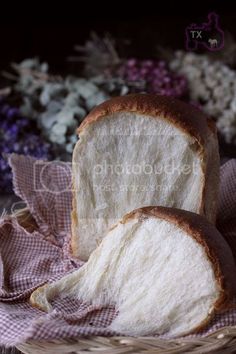 two loaves of bread sitting in a basket next to some flowers and lavenders