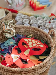 a basket filled with lots of different types of masks and other items on top of a table