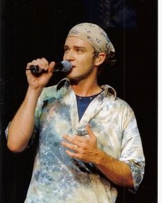 a man with a bandana on his head singing into a microphone