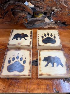 four wooden coasters with bear prints on them sitting on top of a wood table