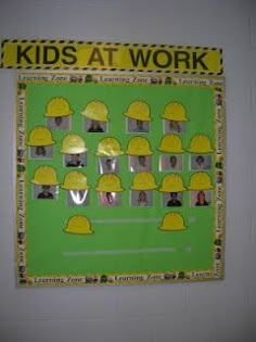 a green bulletin board with yellow hardhats on it's sides and the words kids at work