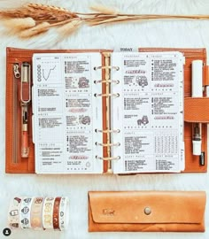 an open planner book sitting on top of a white fur covered floor next to a roll of tape