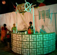 two people standing in front of a green and white display with decorative items on it