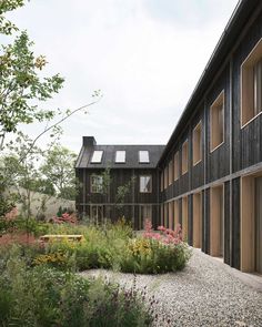 a building with lots of windows next to some flowers and plants on the side of it