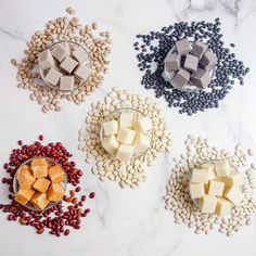 four bowls filled with different types of food on top of a white countertop next to beans