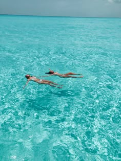 two people floating in the ocean on their backs