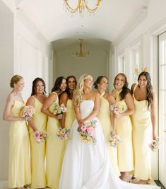 a group of women in yellow dresses standing next to each other and smiling at the camera