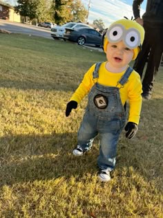 a small child dressed as a minion standing in the grass