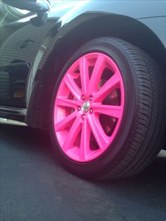 a car with bright pink rims parked on the street