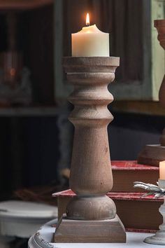 a candle that is on top of a table with other items in the back ground