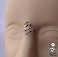 a silver nose ring on top of a mannequin's head with an earring in the shape of a spiral