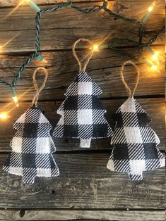 two black and white plaid christmas ornaments hanging from string lights on wooden planked wall