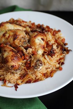 a white plate topped with chicken and rice on top of a green table cloth next to a fork