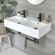 two white sinks in a bathroom under a mirror and potted plant next to it