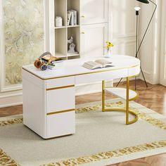 a white desk with gold trim on the top and bottom, sitting in front of a bookcase