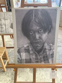 a black and white photo of a young boy in front of easel with chairs behind it