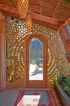 a room with a door and some lights hanging from it's ceiling, surrounded by plants