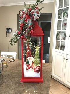 a red lantern with christmas decorations on it in the middle of a kitchen counter top