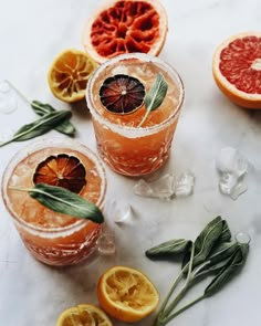 grapefruit, orange and sage spritkled cocktails on a marble table