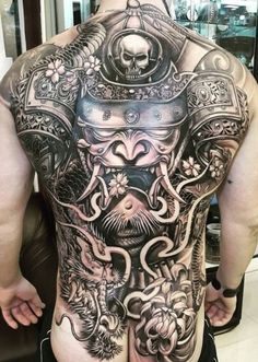 the back of a man's body with tattoos on it and an elaborate design