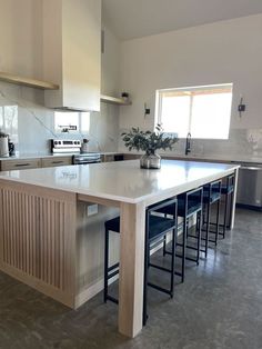 a large kitchen island with stools next to it and a potted plant on the counter