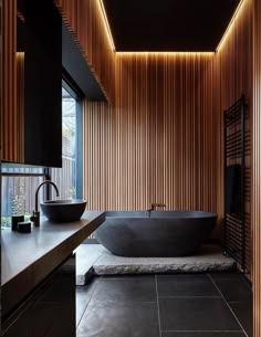 an image of a bathroom setting with wood paneling on the walls and floor, along with a black bathtub