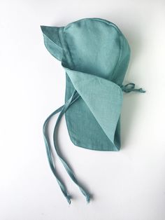 a green hat is laying on top of a white surface and it's tied up to the side