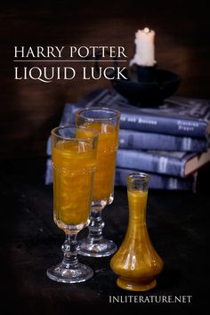 three glasses filled with liquid sitting on top of a table next to stacks of books