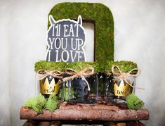 moss covered jars with crowns are sitting on top of a wooden table next to a sign that says i'm eat your love